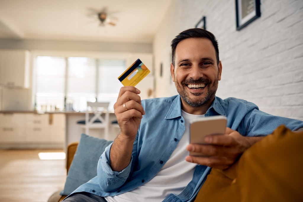 Cliente satisfeito usando cartão de crédito e celular